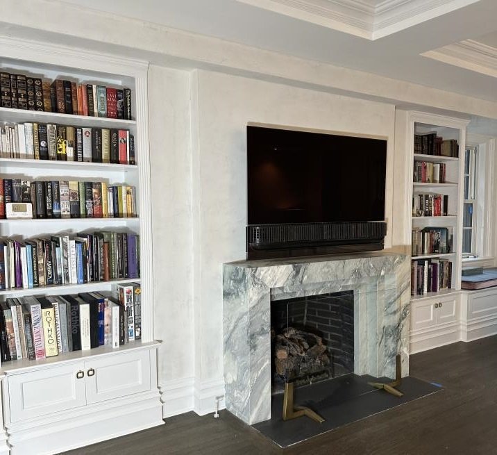 Renovated living room with custom built-in bookshelves and marble fireplace by Dacaj Construction
